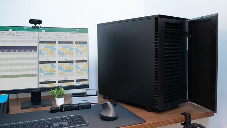 ALTERNATE Workstation Pro naast monitor met spreadsheets, kantooropstelling