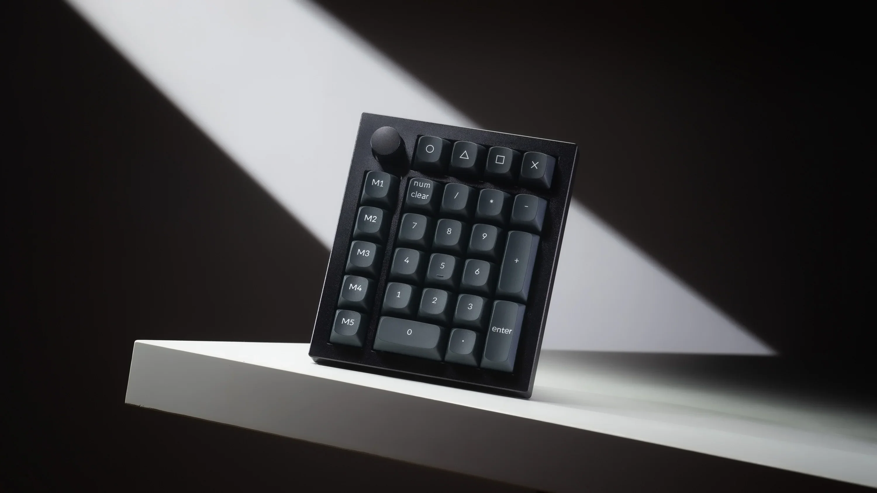 Keychron zwarte mechanische numpad met draaiknop, macrotoetsen en cijfertoetsen op een witte plank